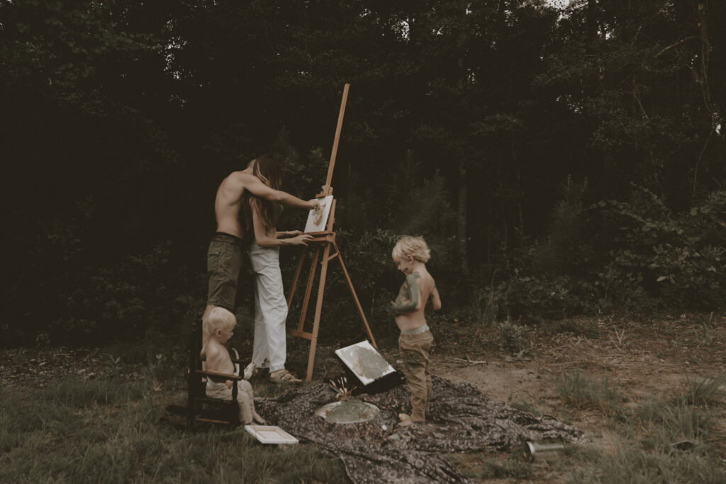 family paints together in the forest during documentary lifestyle photoshoot in North Carolina